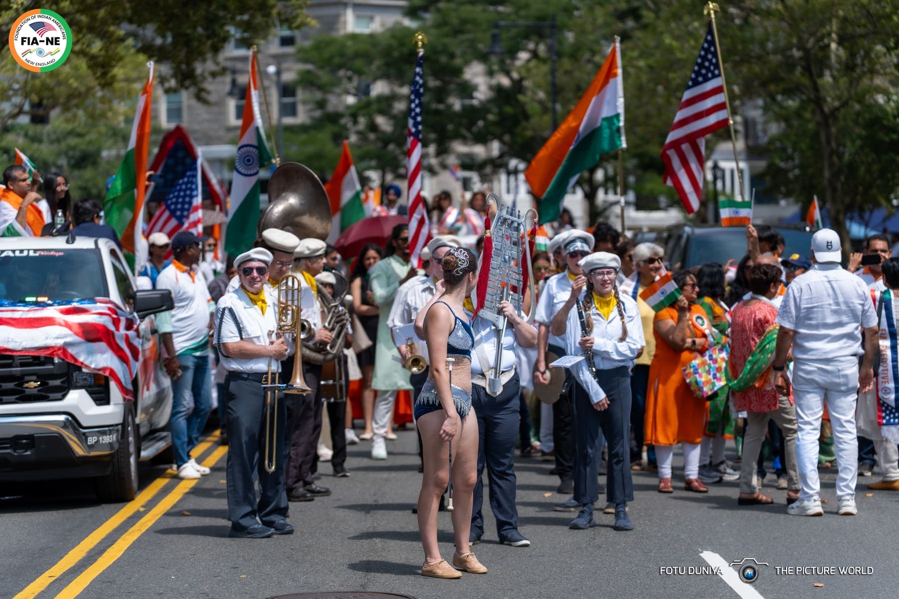 A marching band and crowd holding Indian and American flags lining a Boston street during the parade