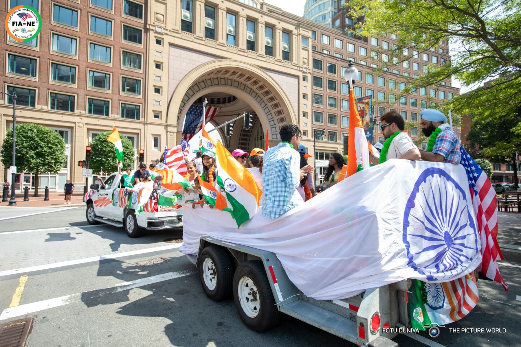 A parade float decorated with the Indian flag's Ashoka Chakra passing beneath Boston's Rowes Wharf archway