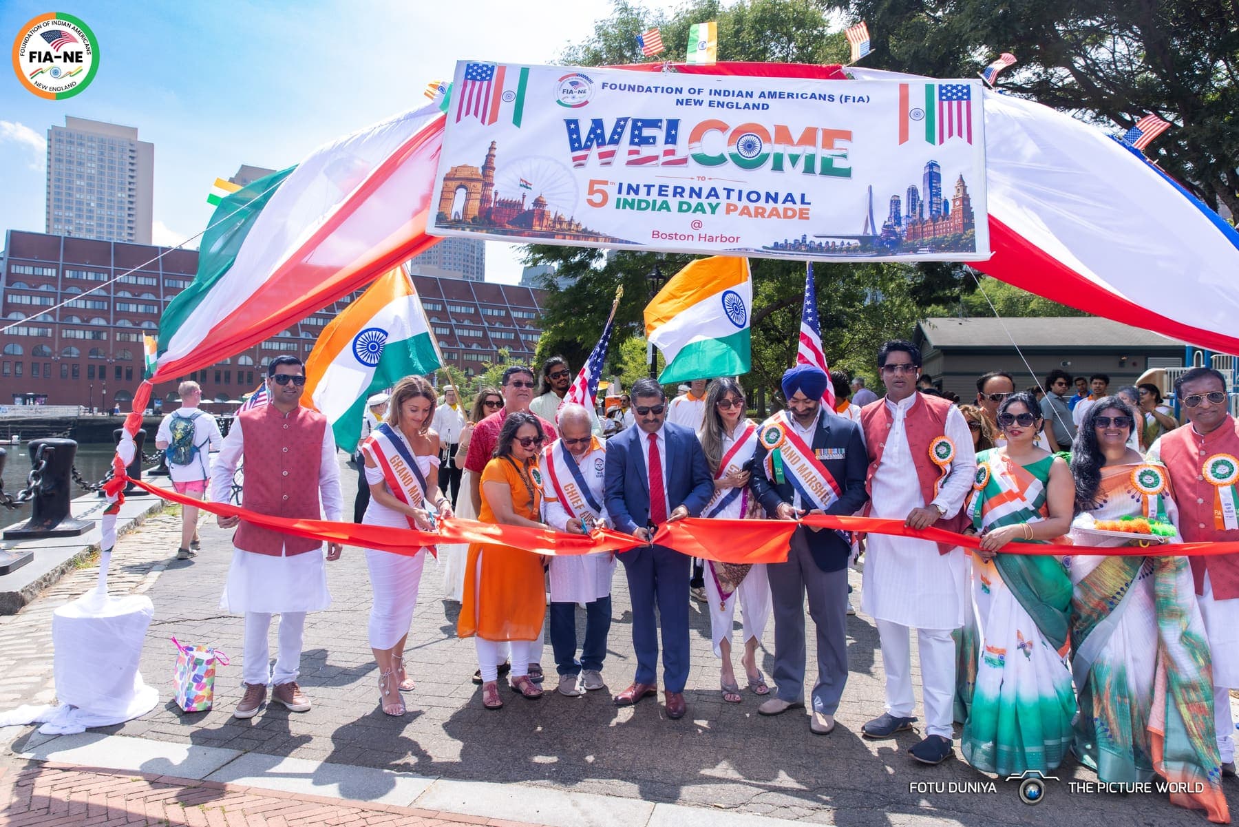 Grand marshals and chief guests cutting the ribbon under the Welcome to the 5th International India Day Parade banner at Boston Harbor